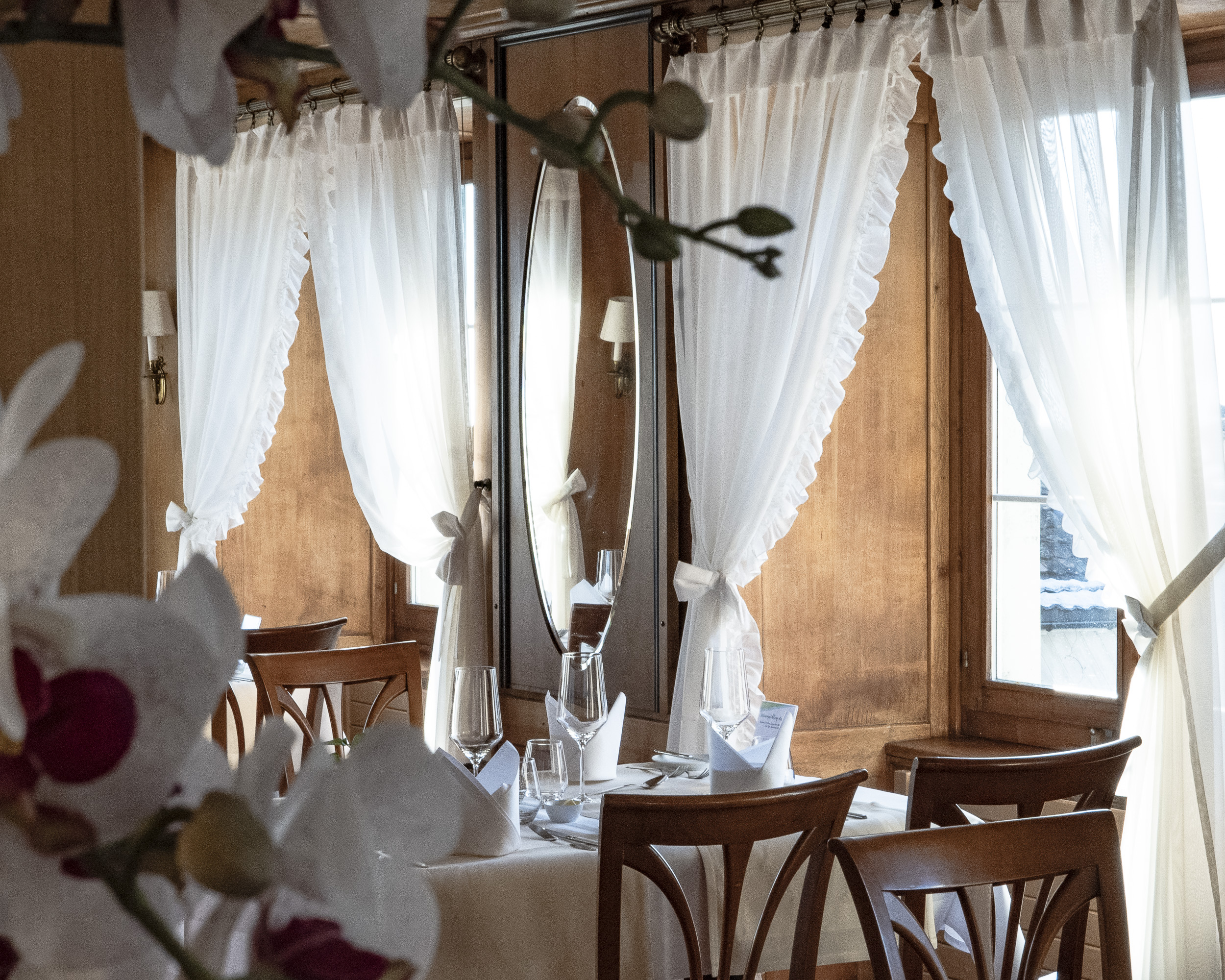 Ein gedeckter Tisch in der historischen Gaststube Rössli Hurden. Vorne Orchideen, an den Fenstern weisse Vorhänge.